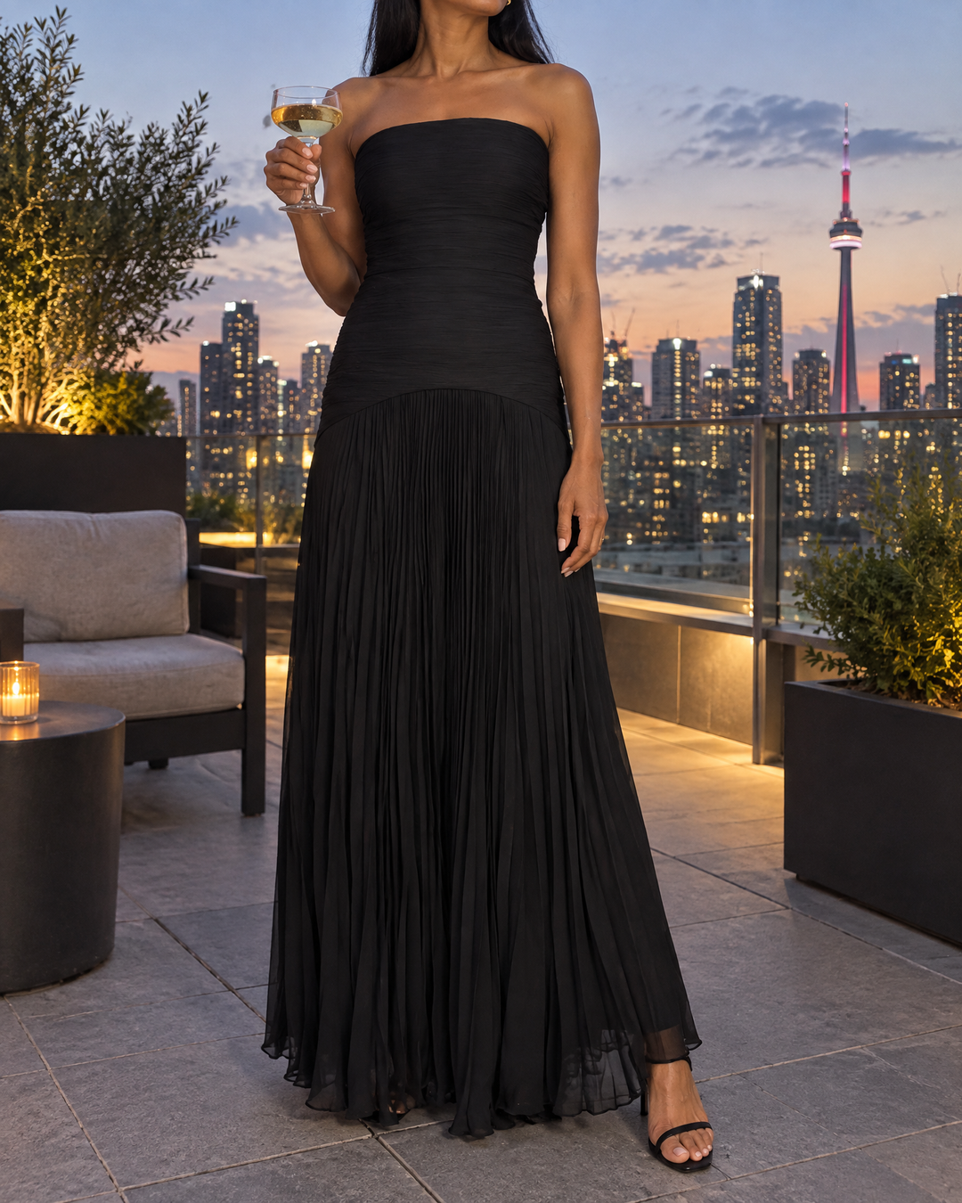 Theodora - Strapless Pleated Maxi Dress in black, on a rooftop at dusk