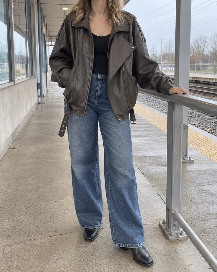 Mirabelle - Oversized Faux Leather Biker Jacket in dark brown, on the train platform on a grey morning
