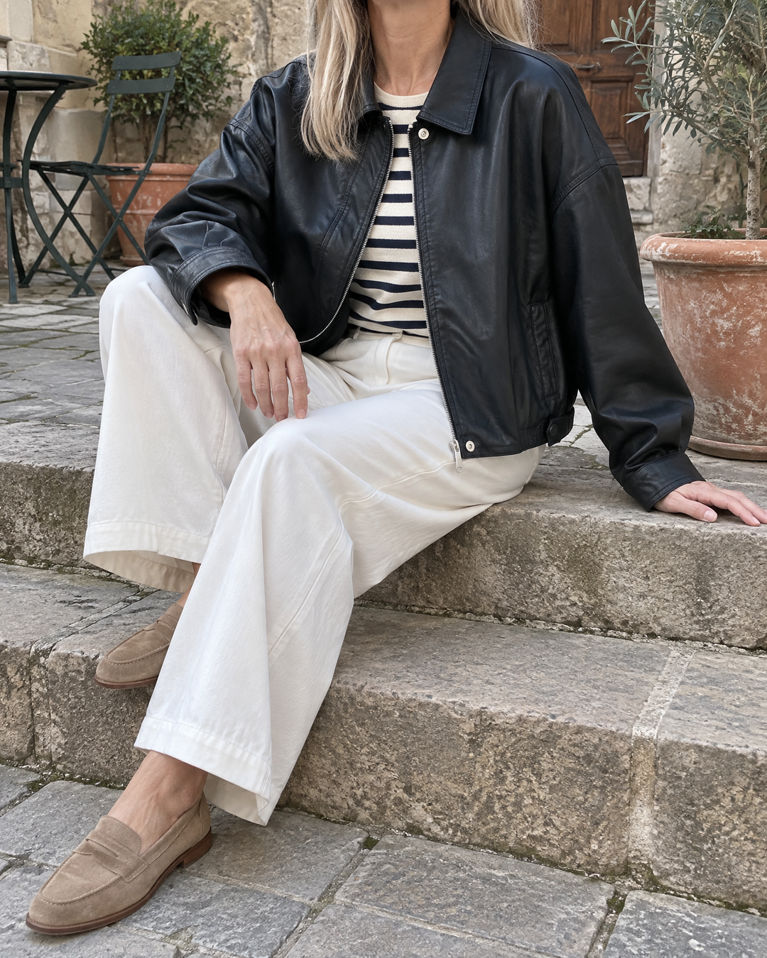 Ysaline - Boxy Faux Leather Jacket in black, on the courtyard steps on a cloudy afternoon
