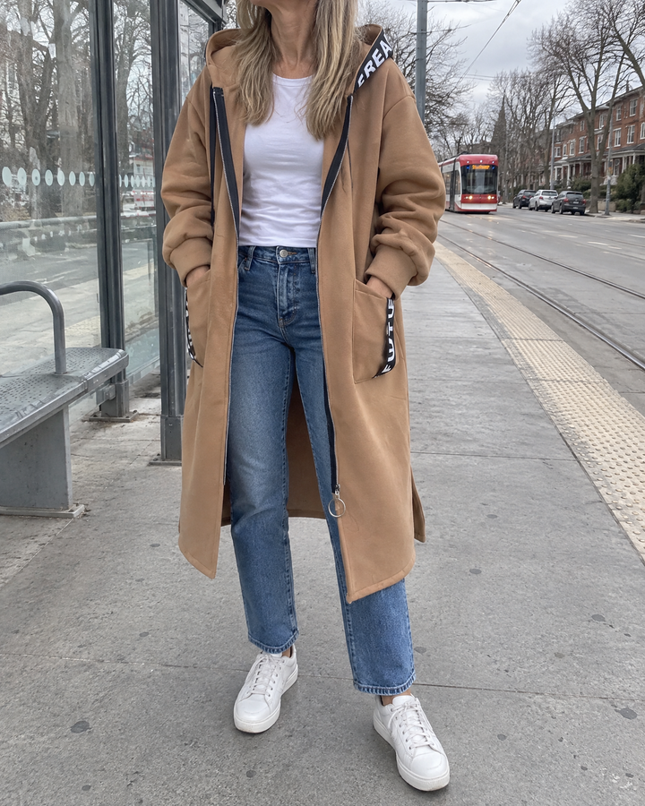 Adrienne - Hooded Fleece Coat in khaki, waiting at a streetcar stop