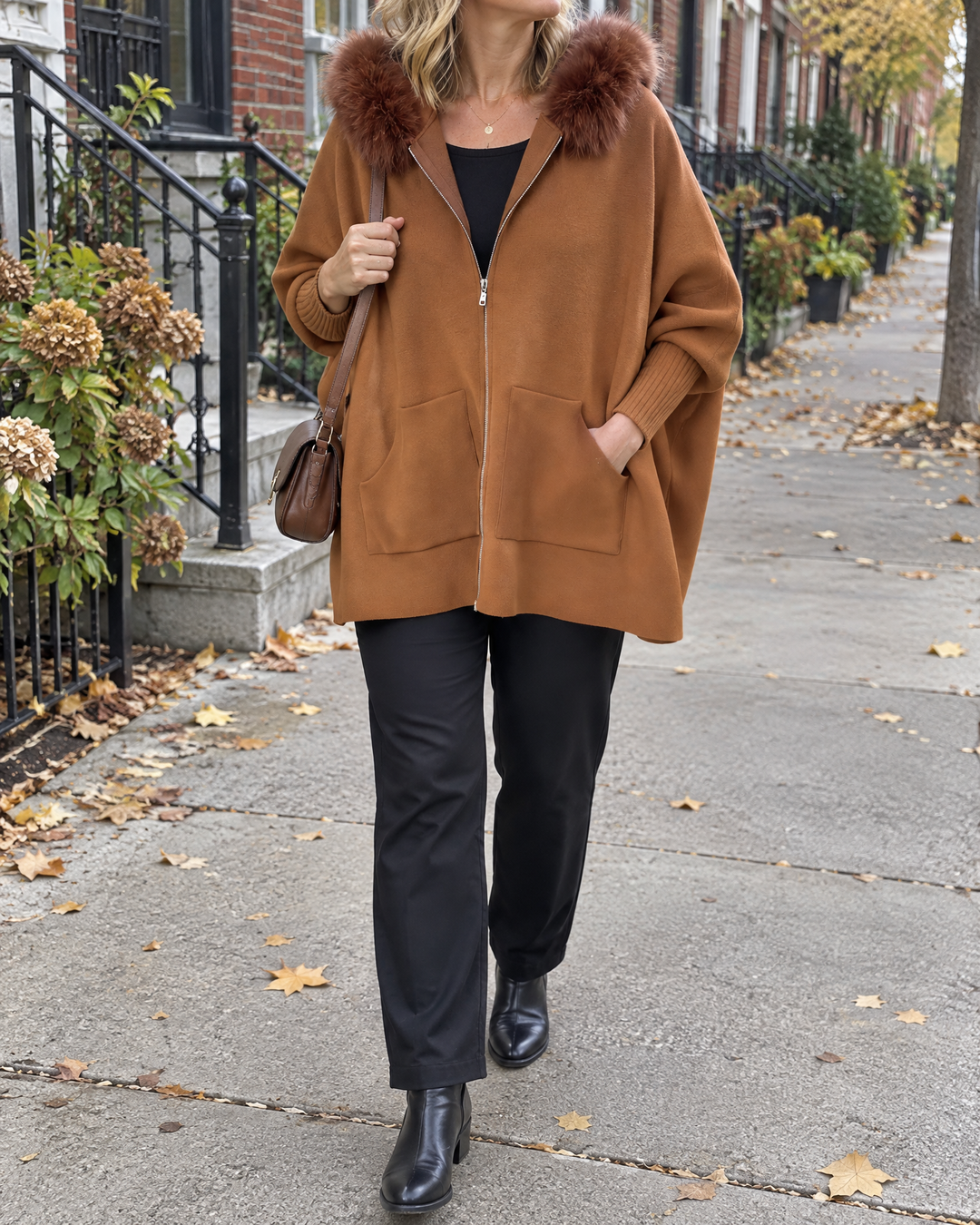 Liliane - Plush Collar Knit Cape in caramel, on a quiet street on an overcast fall morning