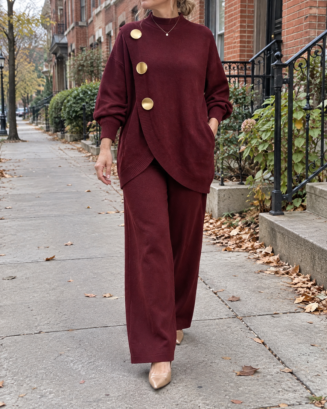 Victorine - Gold Button Knit Set in burgundy, on a quiet city sidewalk on an overcast morning
