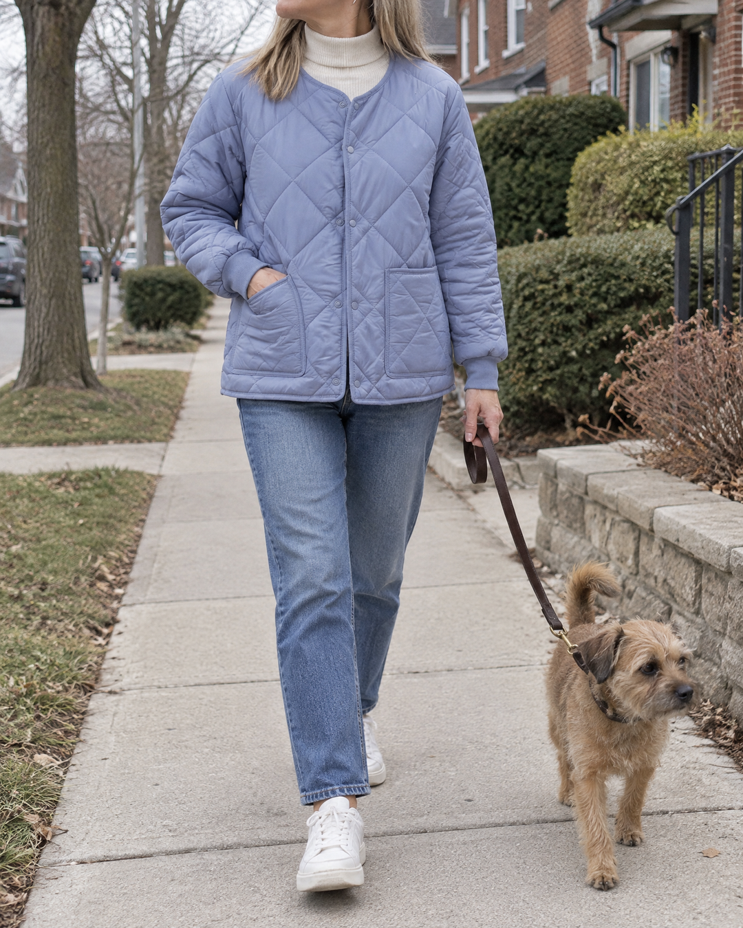 Clementine - Collarless Quilted Jacket in dusty blue, walking the dog on a quiet street