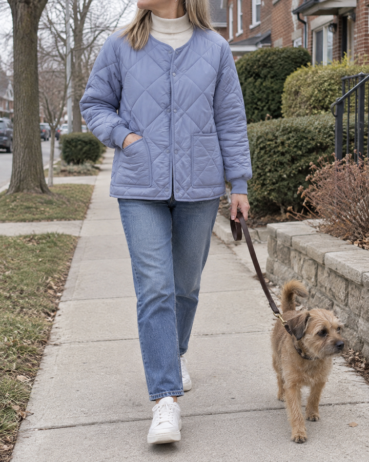 Clementine - Collarless Quilted Jacket in dusty blue, walking the dog on a quiet street