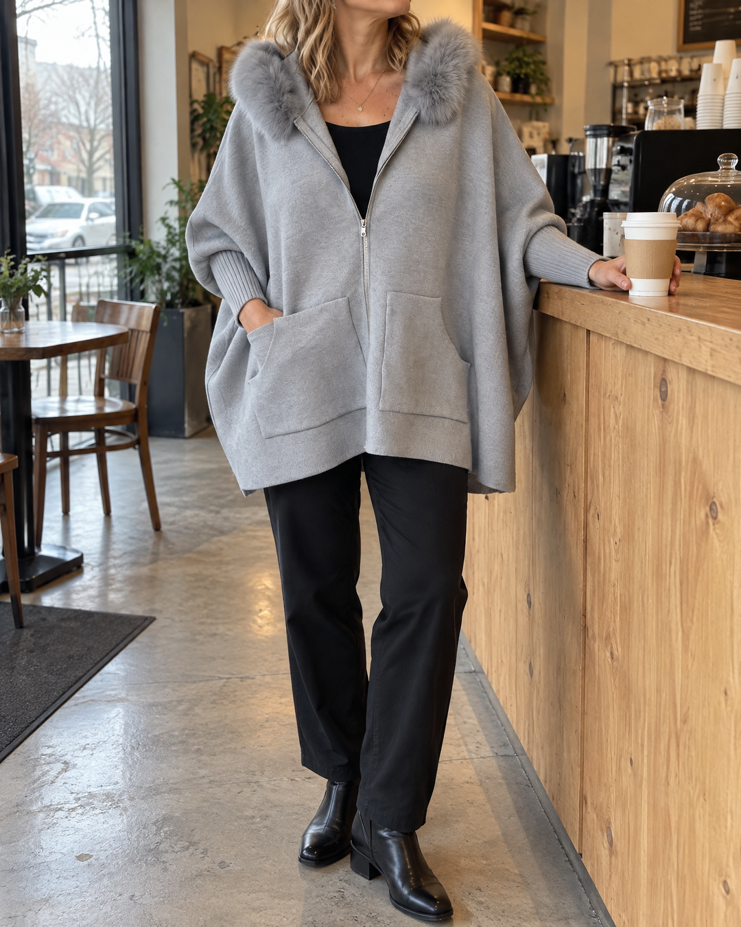 Liliane - Plush Collar Knit Cape in grey, at a café counter